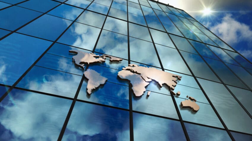 World,Map,Sign,On,Glass,Skyscraper.,Sky,And,Sun,Rays